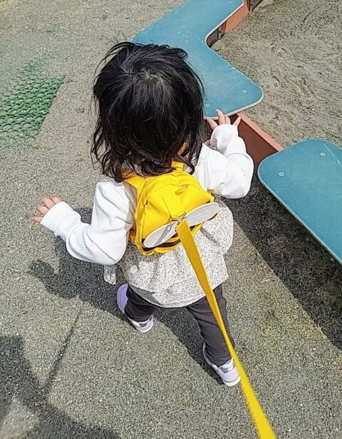 黄色いハチのリュック型ハーネスをつけて遊ぶ幼児の後ろ姿
