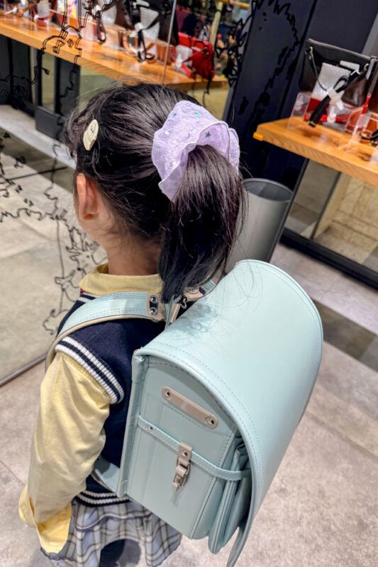 ミントブルーのランドセルを背負っている女の子の後ろ姿